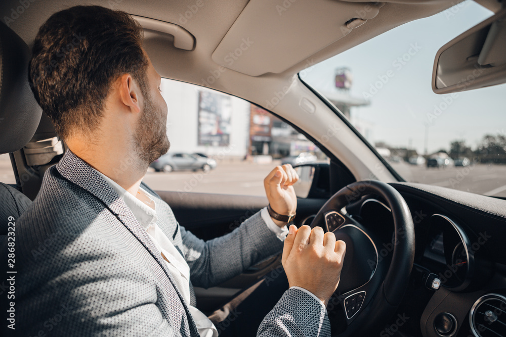 Happy driver in a suit dancing in his luxary car listening to music and enjoying life. Happy driver in a suit dancing in his luxary car listening to music and enjoying life.