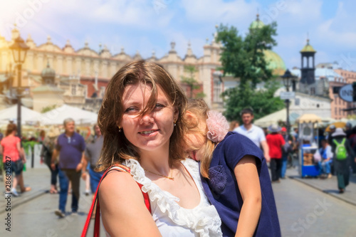 beautiful girl holding tired daughter in main square of Krakow. concept of traveling with kids. Happy parents do not leave their children at home © sommersby