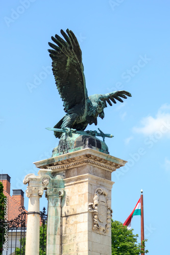 bronze statue of eagle with open wings holding sword in its claws at main gate of Buda fortress in Budapest, Hungary