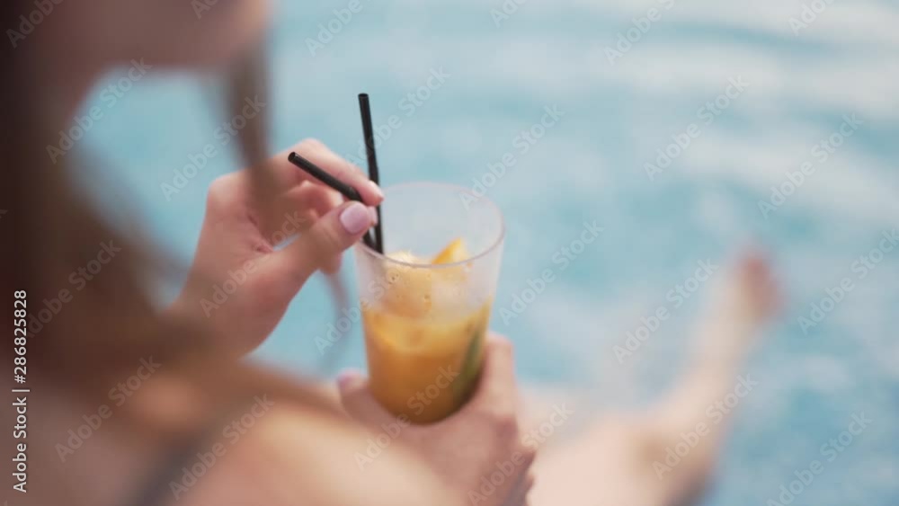 Soft focus shot of woman at the swimming pool enjoying a coctail Soft focus shot of woman at the swimming pool enjoying a coctail
