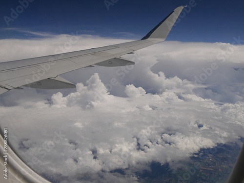 Storm clouds seen from an airplane window  with an airplane wing in view.