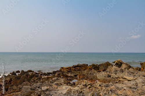 Rocky shore with blue sea and mist on the ocean. Natural landscape. Summer travel background. Dark day.
