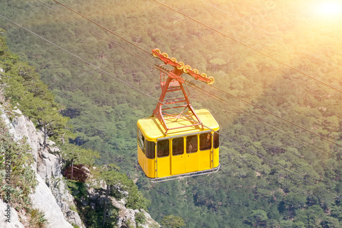 yellow cabin moves up cable car over cliffs photo
