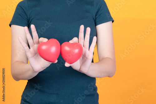 Young woman holding two red hearts in hands. Concept for relationships,valentine or health Space for design, closed up half figured and studio lighting shooting.