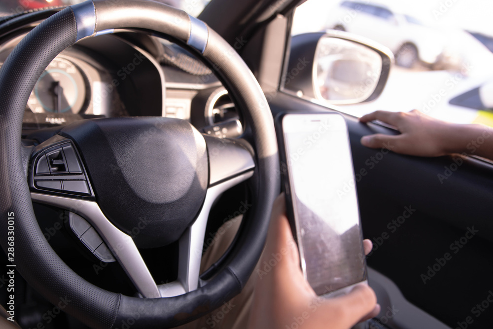 Male sitting in car and using his smartphone