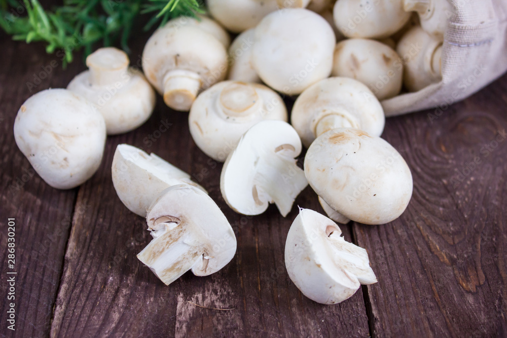 Champignon mushrooms in a bag on a dark background with a sprig of greenery Champignon mushrooms in a bag on a dark background with a sprig of greenery