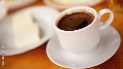 A cup of hot coffee in a white cup on wooden background