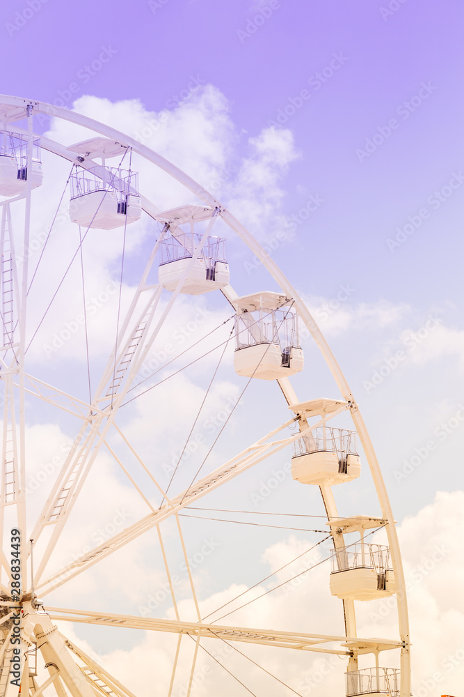 Ferris wheel on the colorful cloudy sky. Background concept of happy holidays time.