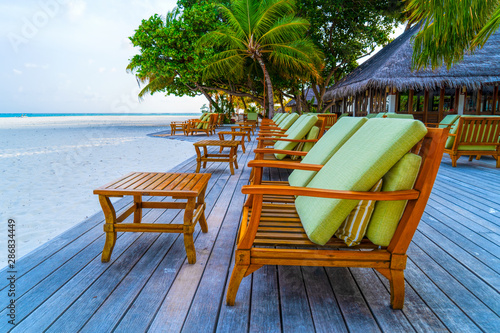 Beach chairs on the white sand on the shore of a beautiful tropi