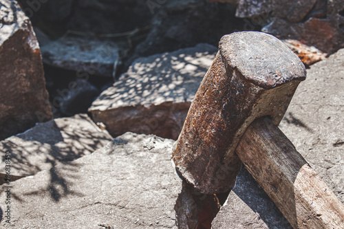 Rusty sledgehammer on broken bricks and concrete stones.
