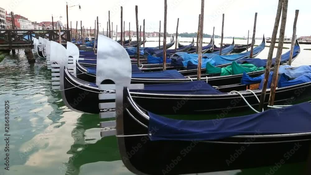 Early morning in venice. Gondolas at the pier. No people around. Still, calm water gentrly rocking the row of sleeping boats. Early morning in venice. Gondolas at the pier. No people around. Still, calm water gentrly rocking the row of sleeping boats.