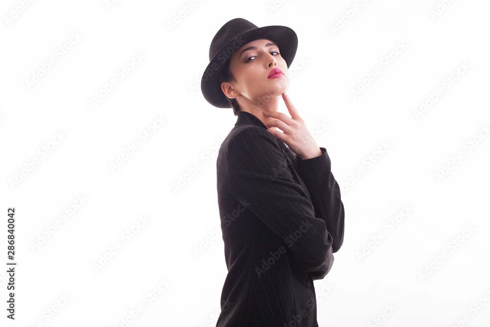 Caucasian beauty posing with confidence in front of the camera in studio wearing a retro hat and stylish black jacket over white background Caucasian beauty posing with confidence in front of the camera in studio wearing a retro hat and stylish black jacket over white background