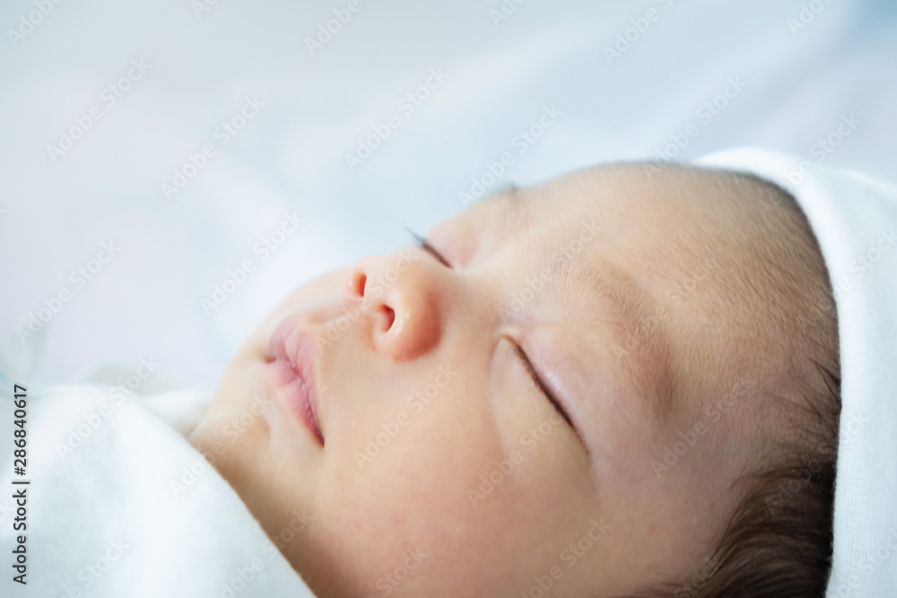 Closeup head shot of newborn baby boy sleeping in bed and lying in white clothes on white. Closeup head shot of newborn baby boy sleeping in bed and lying in white clothes on white.