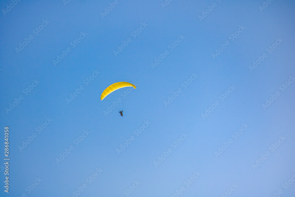 Paraglider floating through a blue sky over Camps Bay, Cape Town. Paraglider floating through a blue sky over Camps Bay, Cape Town.