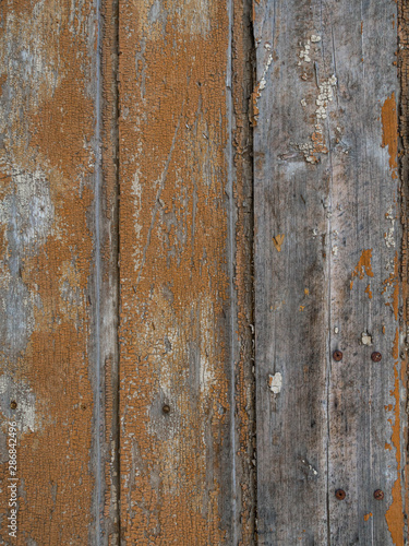 An old wooden wall texture with peeling faded brown paint