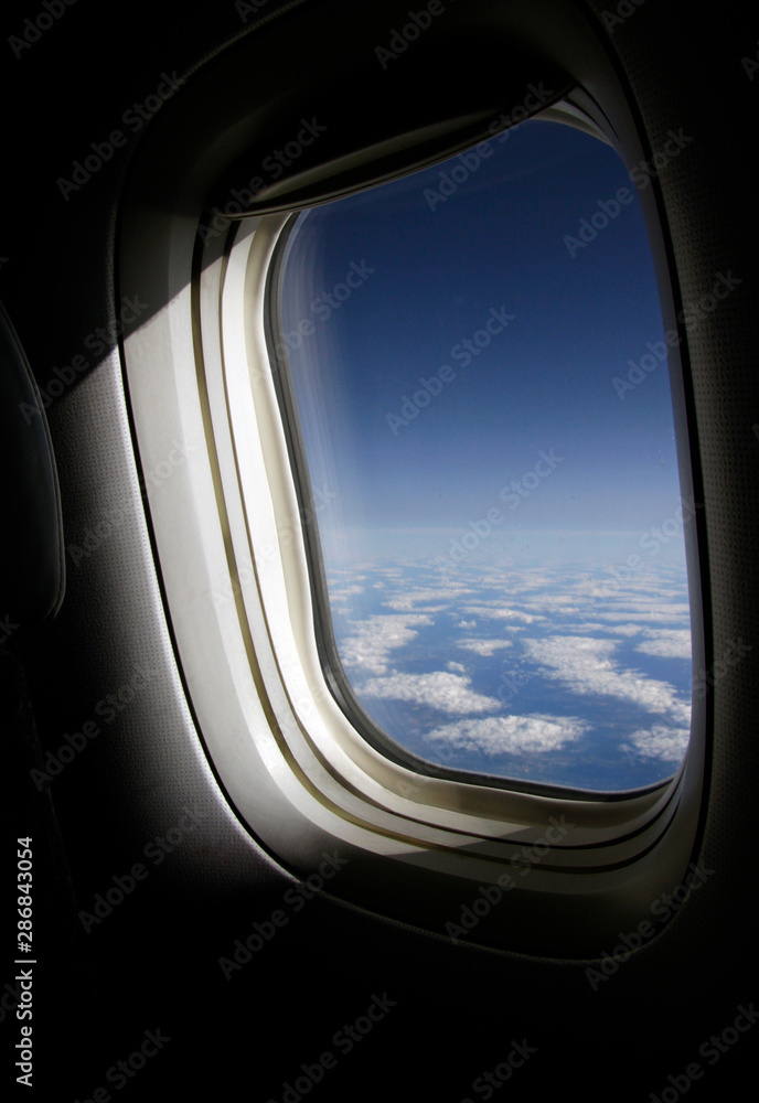 The sun shines through a plane window on cruising altitude