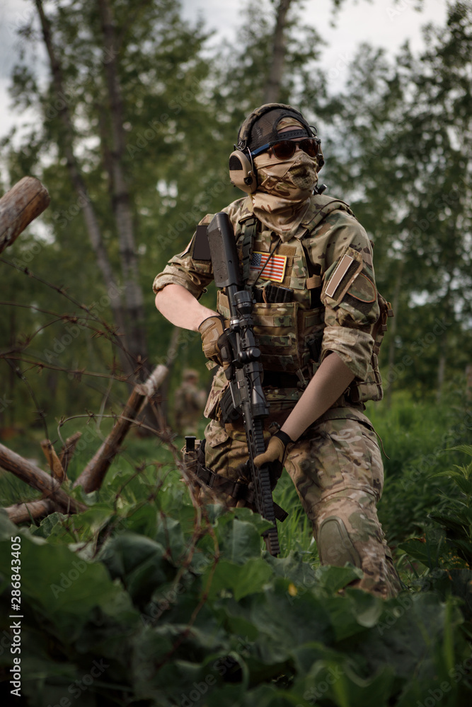 Airsoft fighter in full ammunition with a weapon at the time of game. A warrior runs and shoots on move