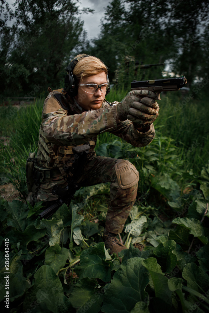 Airsoft fighter in full ammunition with a weapon at the time of game. A warrior runs and shoots on move Airsoft fighter in full ammunition with a weapon at the time of game. A warrior runs and shoots on move