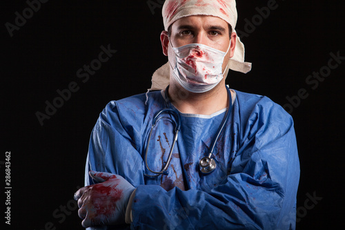 Portrait man in doctor costume for halloween with blood on his hands photo