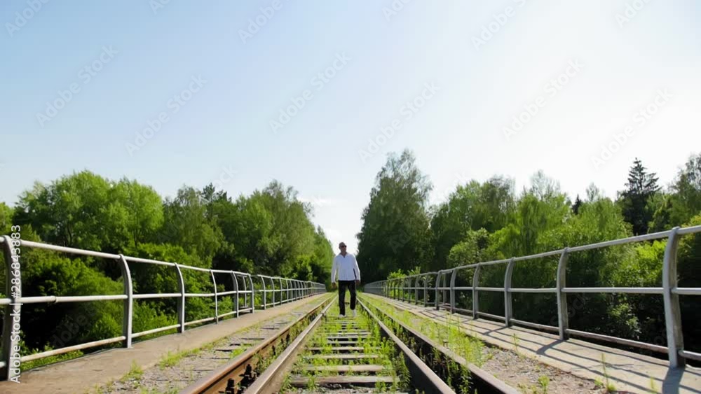 A man going along on an abandoned railway bridge from afar. Full shot. A man going along on an abandoned railway bridge from afar. Full shot.