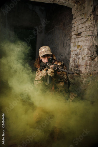 Fighter in full ammunition with guns in smoke shoot in an abandoned building