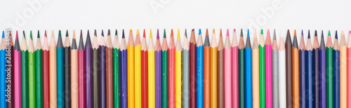 Panoramic shot of straight line of color pencils isolated on white