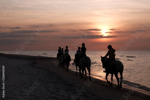 girls horseriding on beach at sunset