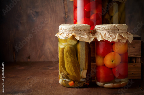 Obraz na płótnie Homemade pickled tomato and cucumber in glass jars on an wooden rustic background w salonie