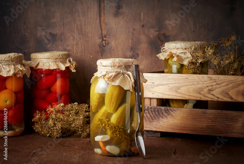 Obraz na płótnie Homemade pickled tomato and cucumber in glass jars in wooden rustic box w salonie