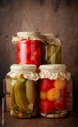 Obraz na płótnie Homemade pickled tomato and cucumber in glass jars on an wooden rustic background w salonie