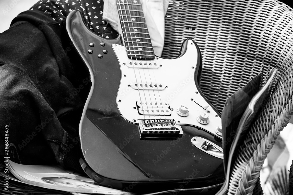 Guitare électrique noir et blanche posée sur une chaise Stock Photo