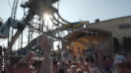Blurred - many people dance in swimsuits at a water park party. Animators entertain the crowd