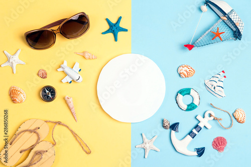 Flat lay travel concept with vacation accessories and symbols and copy space for text on a yellow and blue background.