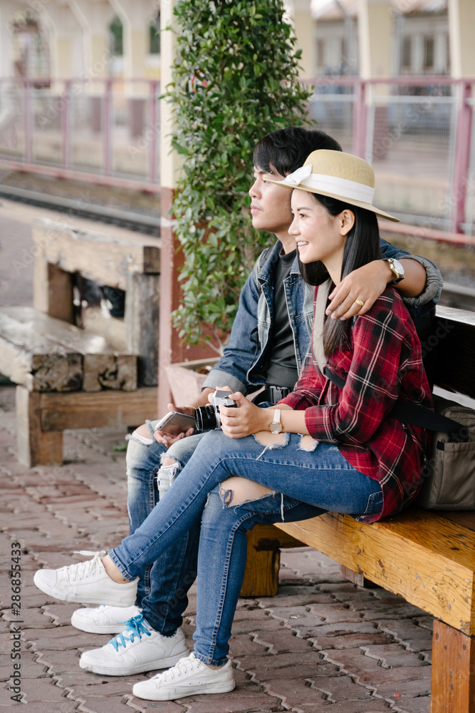 Couple of travel photographer enjoys taking photo during their trip at railway station. Asian travelers with camera having fun making pictures while waiting for train. Couple of travel photographer enjoys taking photo during their trip at railway station. Asian travelers with camera having fun making pictures while waiting for train.