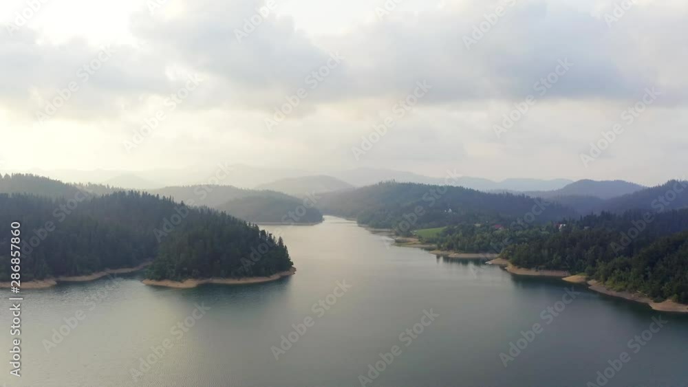 Aerial view of Lokve lake surrounded by hills and mountains with coniferous forest. Flying Over the Lokve lake in Croatia. Nature background in 4K resolution. Aerial view of Lokve lake surrounded by hills and mountains with coniferous forest. Flying Over the Lokve lake in Croatia. Nature background in 4K resolution.