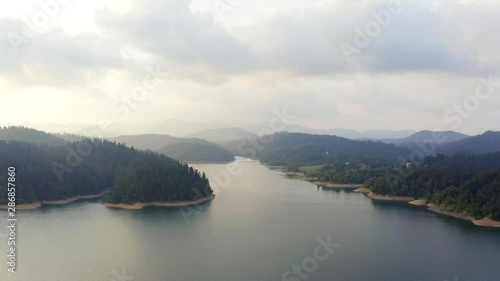 Aerial view of Lokve lake surrounded by hills and mountains with coniferous forest. Flying Over the Lokve lake in Croatia. Nature background in 4K resolution.