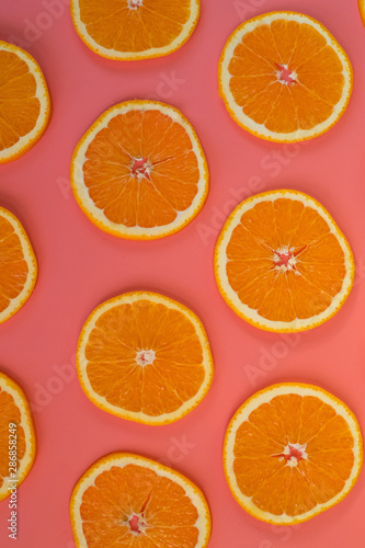 Background of sliced ripe oranges on a pink background vertical.