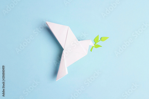 Photo Paper origami dove of peace with olive branch on a blue background