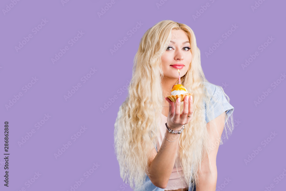 Happy lovely curly young woman holding birthday cupcake with candle Happy lovely curly young woman holding birthday cupcake with candle