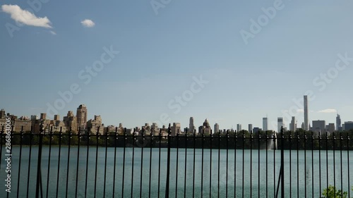 PANNING view of NYC buildings and neaby fence and water within Central Park. photo