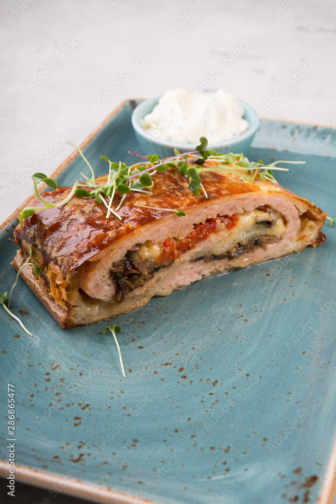 Slice of meat roll cake with sour cream