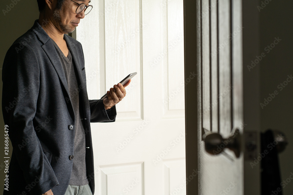 Asian businessman with smartphone at the door Asian businessman with smartphone at the door