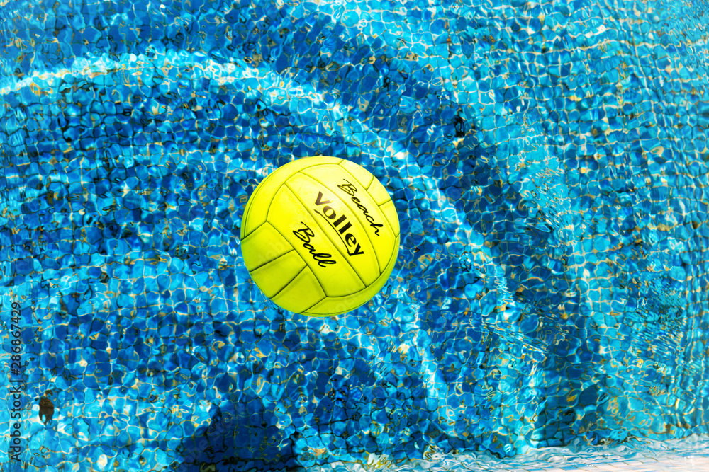 Rubber beach volleyball, inside swimming pool, on a bright summer day.