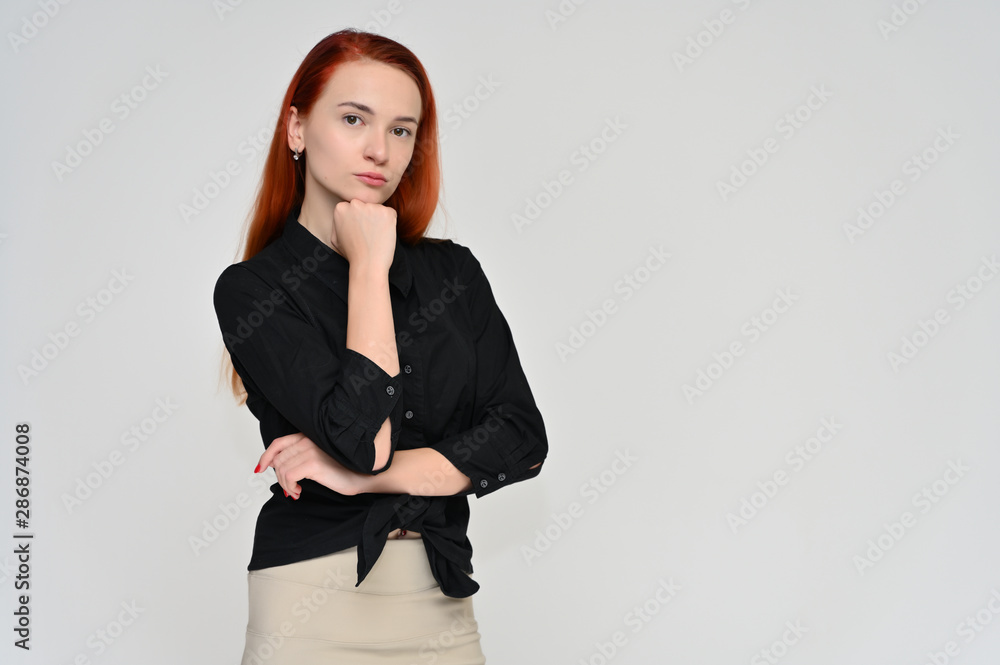 Portrait of a pretty red-haired girl, a happy young woman manager in a business suit on a white background in studio. Smiling, showing different emotions. Portrait of a pretty red-haired girl, a happy young woman manager in a business suit on a white background in studio. Smiling, showing different emotions.