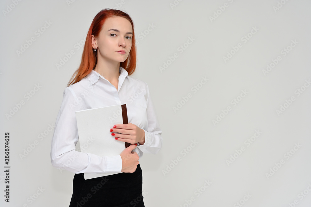 Portrait of a pretty red-haired girl, a happy young woman manager in a business suit on a white background in studio. Smiling, showing different emotions. Portrait of a pretty red-haired girl, a happy young woman manager in a business suit on a white background in studio. Smiling, showing different emotions.