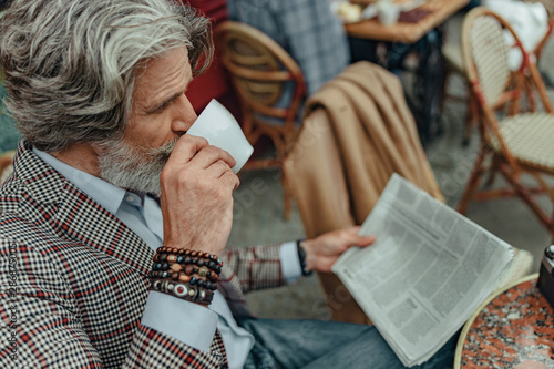 Elegant senior man drinking coffee at outdoor cafe