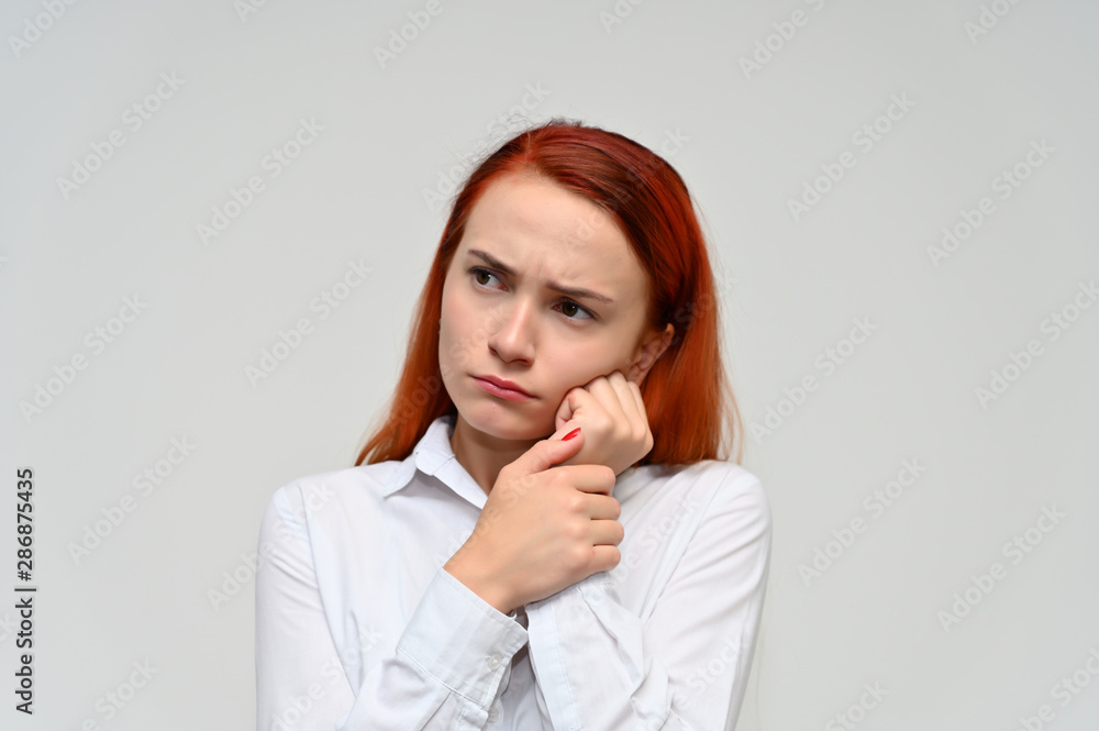 Close-up Portrait of a pretty red-haired girl, a happy young woman manager in a white shirt on a white background in studio. Smiling, showing different emotions. Close-up Portrait of a pretty red-haired girl, a happy young woman manager in a white shirt on a white background in studio. Smiling, showing different emotions.