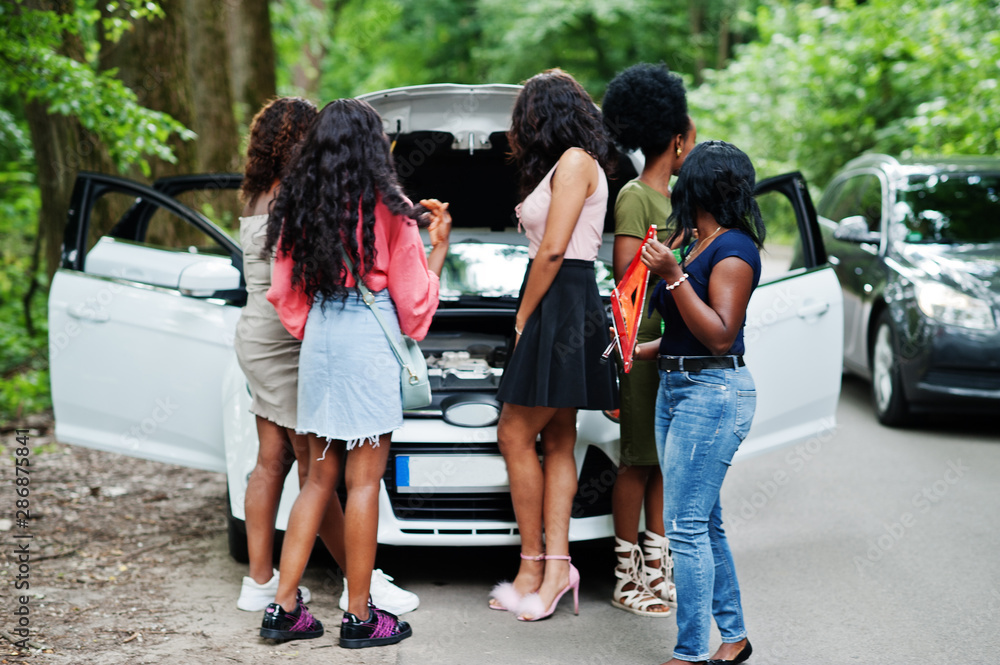 Obraz premium Group of five african american traveler girls looking at broken car open hood.