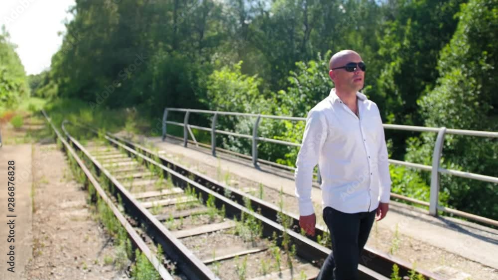 A bald man going along on an abandoned railway bridge and sings. Close up shot. A bald man going along on an abandoned railway bridge and sings. Close up shot.