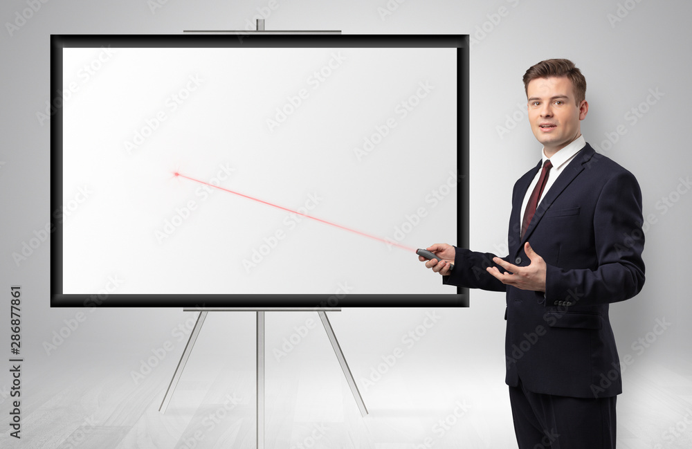 Young businessman with laser pointer and copyspace white wall Young businessman with laser pointer and copyspace white wall